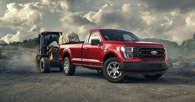Red 2021 Ford F-150 hauling cement at a construction work site.