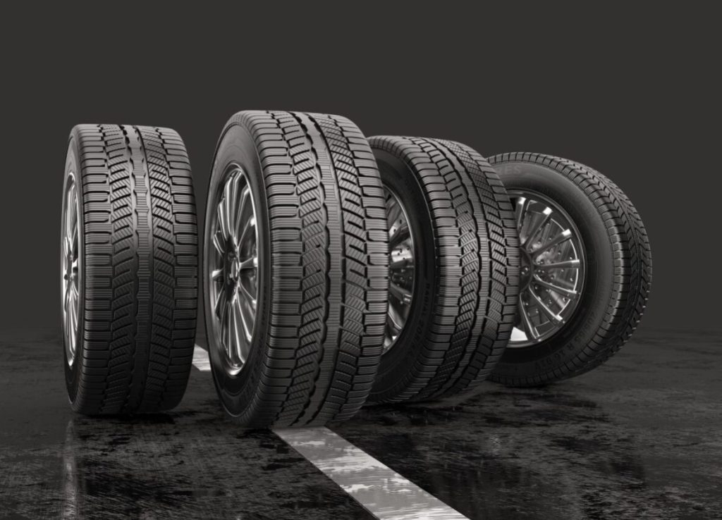 The image features four large black tires, each with a different size, sitting on a black background. The tires are arranged in a row, with one on the left, one in the middle, one on the right, and the last one at the far right. The tires are likely meant to showcase the variety of tire options available at a local Ford dealership.